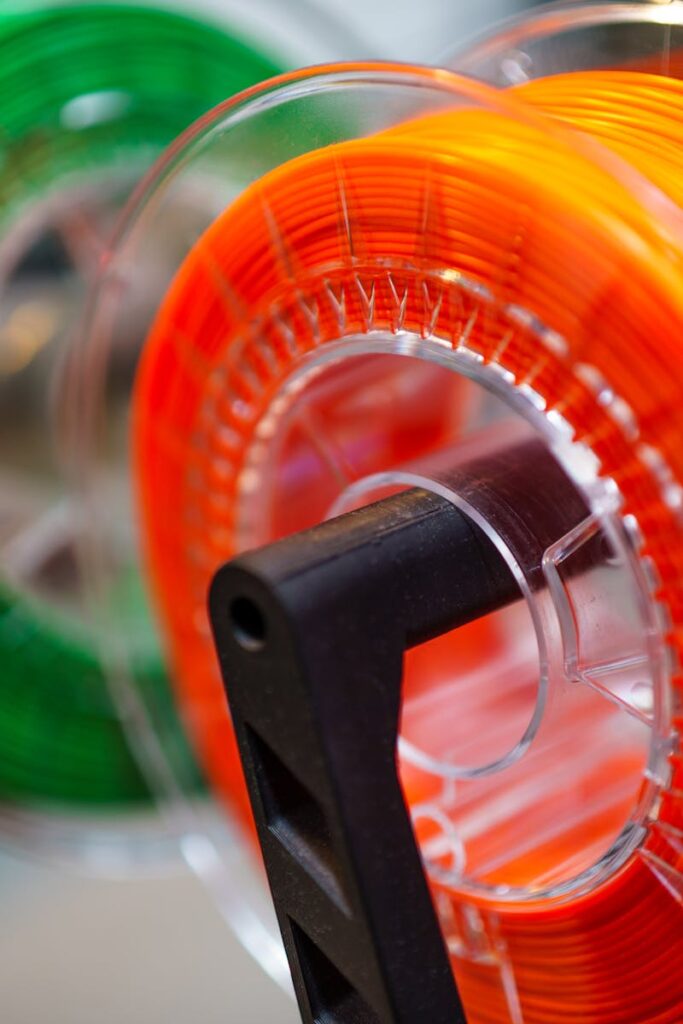 pexels-photo-31336838-31336838 Vibrant orange and green 3D printer filament spools for innovative manufacturing uses.